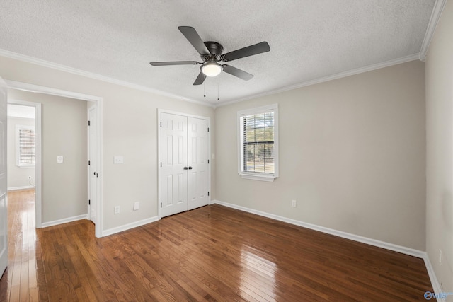 unfurnished bedroom featuring ceiling fan, dark wood-type flooring, crown molding, a textured ceiling, and a closet