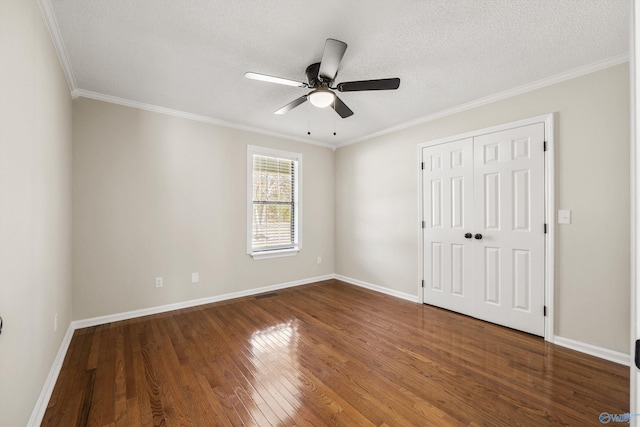 unfurnished bedroom with a textured ceiling, ceiling fan, crown molding, dark wood-type flooring, and a closet