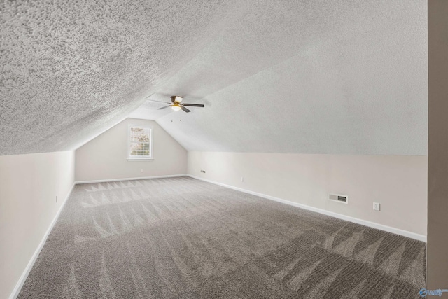 additional living space with a textured ceiling, carpet floors, vaulted ceiling, and ceiling fan