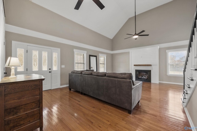 living room featuring a fireplace, wood-type flooring, high vaulted ceiling, and ceiling fan