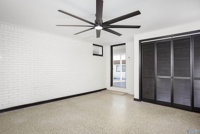 unfurnished bedroom with ceiling fan and brick wall