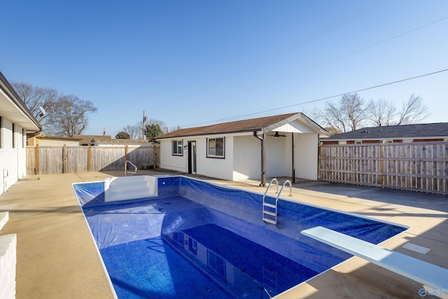 view of swimming pool featuring an outbuilding, a diving board, and a patio