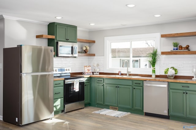 kitchen featuring decorative backsplash, sink, green cabinetry, stainless steel appliances, and butcher block counters