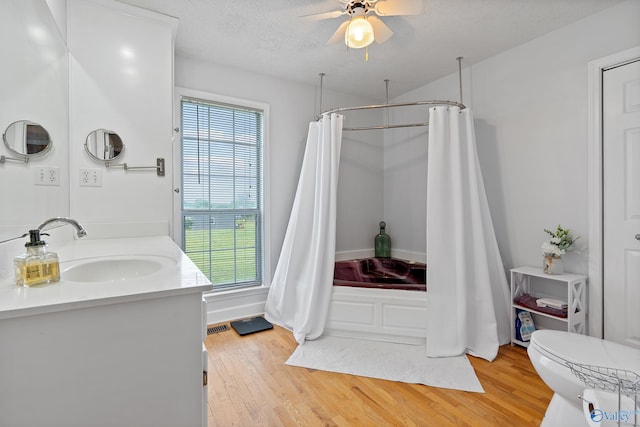 full bathroom with ceiling fan, vanity, toilet, shower / bathtub combination with curtain, and wood finished floors