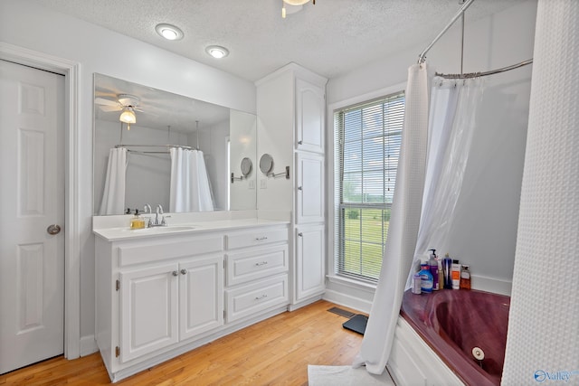 full bath featuring vanity, a bathtub, a textured ceiling, and wood finished floors