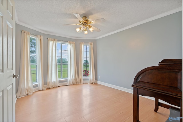 sitting room with baseboards, light wood-style flooring, a textured ceiling, and ceiling fan