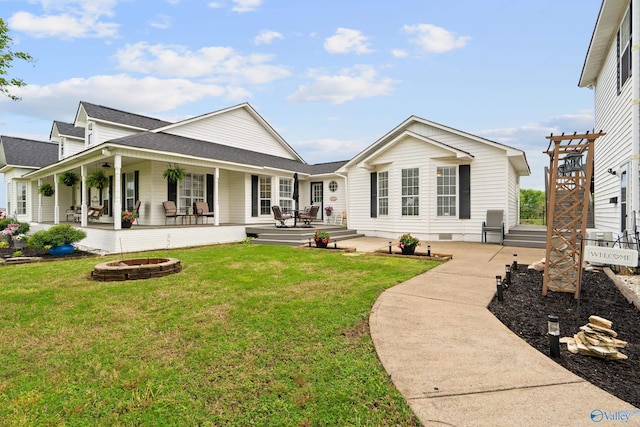 back of house featuring a shingled roof, an outdoor fire pit, a porch, crawl space, and a lawn