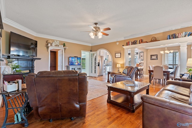 living room featuring crown molding, a textured ceiling, ceiling fan with notable chandelier, and wood finished floors