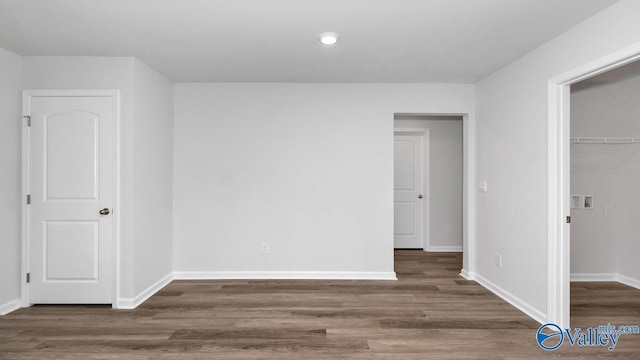 unfurnished bedroom with a walk in closet, dark hardwood / wood-style floors, and a closet