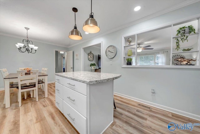 kitchen featuring visible vents, a kitchen island, ornamental molding, white cabinets, and light wood-style floors