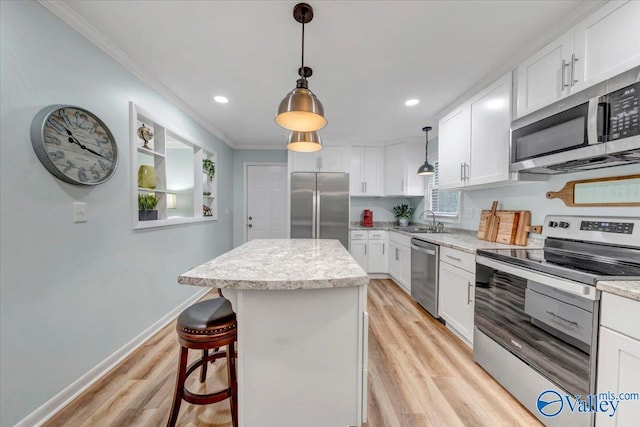 kitchen with baseboards, light wood-style floors, appliances with stainless steel finishes, crown molding, and a center island