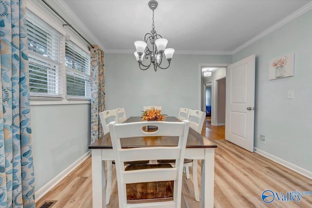 dining room featuring visible vents, an inviting chandelier, crown molding, light wood finished floors, and baseboards