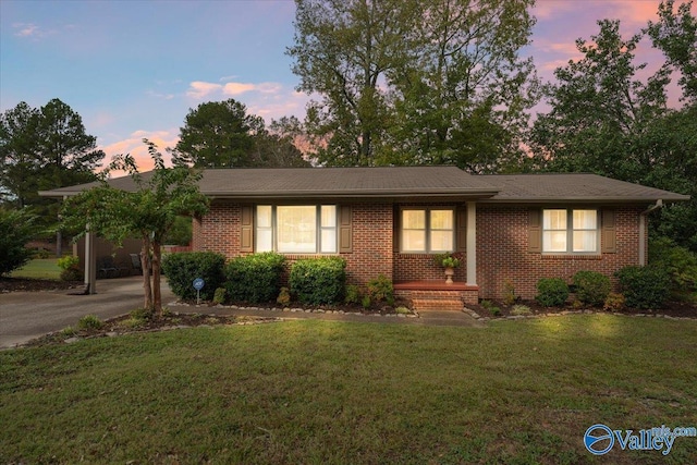 single story home with brick siding and a yard