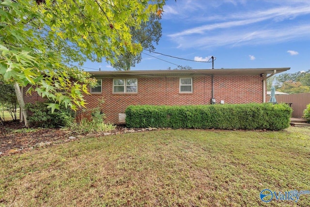 view of side of home featuring brick siding and a lawn