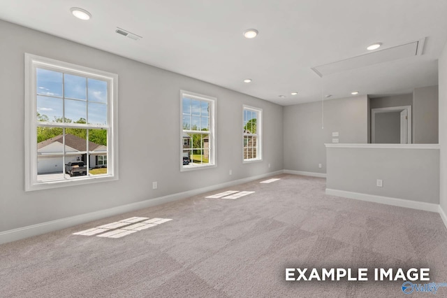 carpeted spare room featuring visible vents, plenty of natural light, attic access, and baseboards