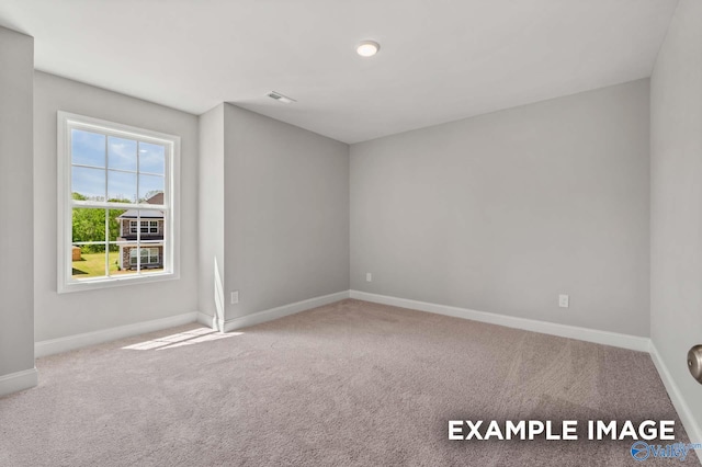 carpeted spare room with visible vents and baseboards