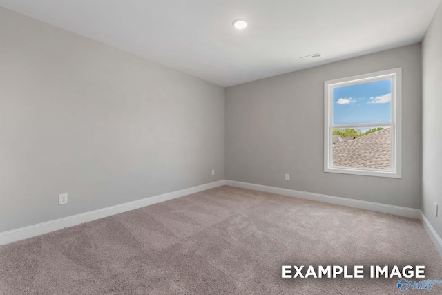 carpeted spare room with visible vents and baseboards