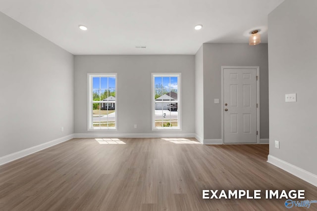 unfurnished living room featuring visible vents, baseboards, wood finished floors, and recessed lighting