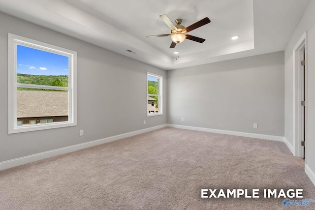 carpeted empty room featuring visible vents, baseboards, a raised ceiling, a ceiling fan, and recessed lighting