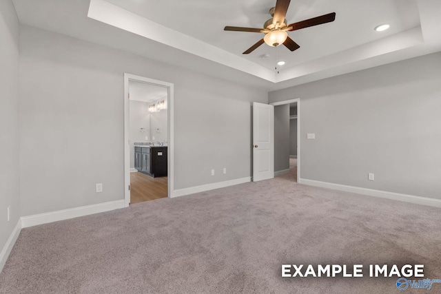 unfurnished bedroom featuring baseboards, a tray ceiling, carpet flooring, and recessed lighting