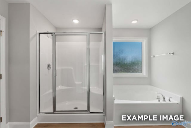 bathroom with a stall shower, a garden tub, and baseboards