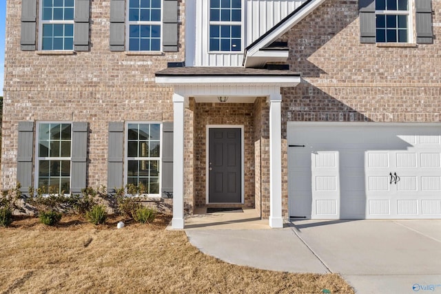 property entrance with concrete driveway, brick siding, board and batten siding, and an attached garage