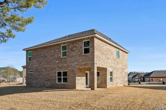 back of house with brick siding and a lawn