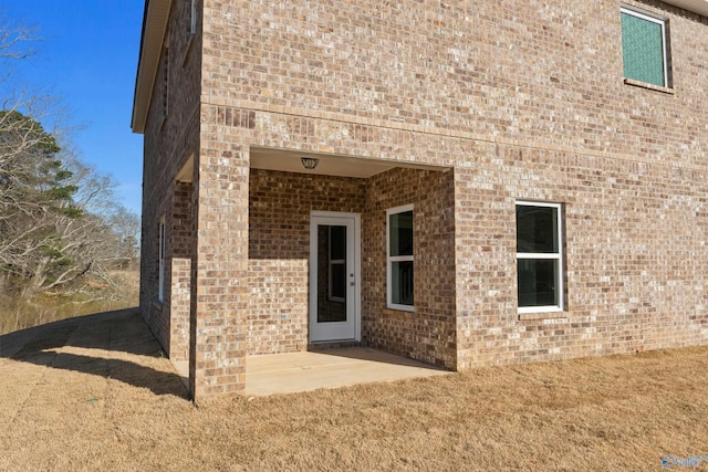 view of exterior entry with a patio area and brick siding