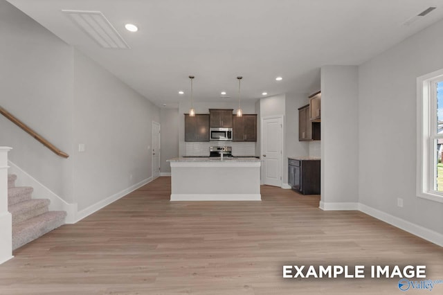 kitchen featuring light wood finished floors, open floor plan, stainless steel appliances, light countertops, and recessed lighting