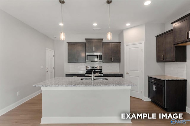 kitchen featuring appliances with stainless steel finishes, a sink, dark brown cabinets, and wood finished floors