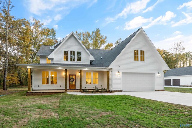 modern inspired farmhouse featuring an attached garage, concrete driveway, a porch, and a front yard