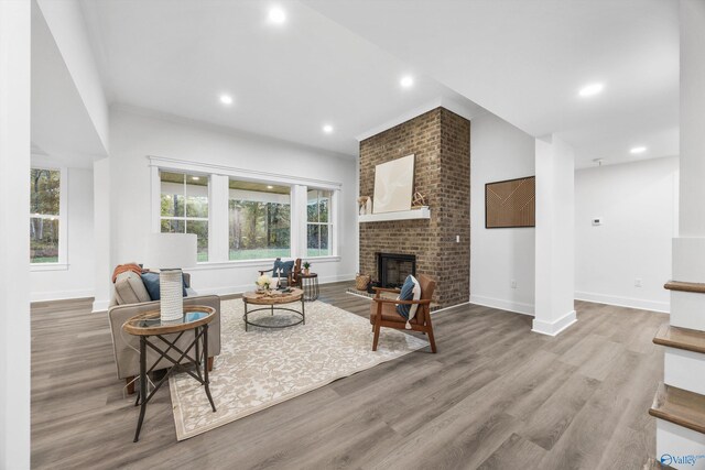 living area with baseboards, a brick fireplace, recessed lighting, and wood finished floors