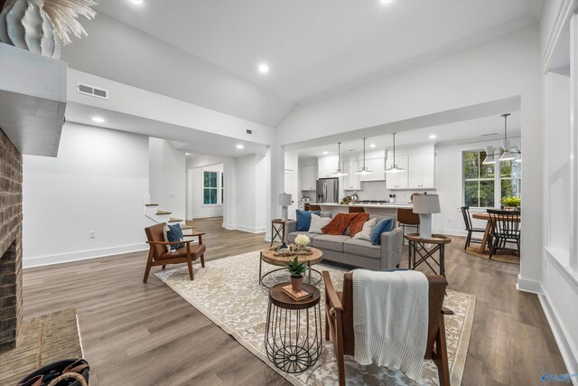 living area with high vaulted ceiling, visible vents, baseboards, and light wood-style floors