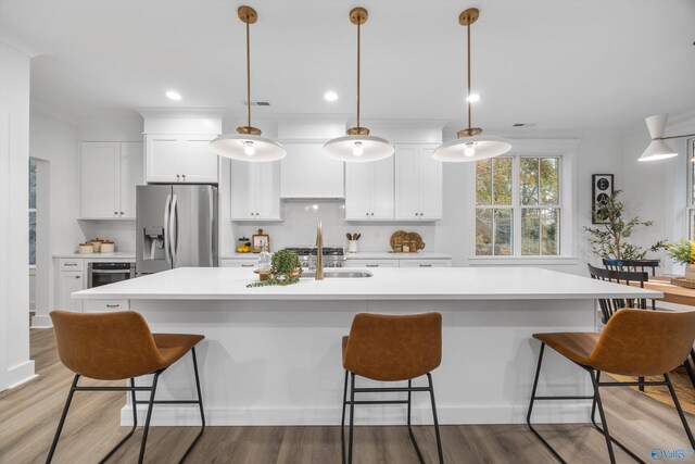 kitchen featuring light wood-style flooring, a kitchen breakfast bar, white cabinetry, and stainless steel fridge with ice dispenser