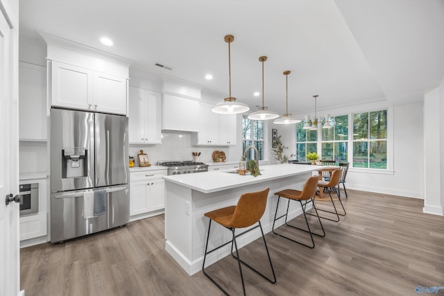 kitchen featuring wood finished floors, light countertops, white cabinetry, a sink, and appliances with stainless steel finishes