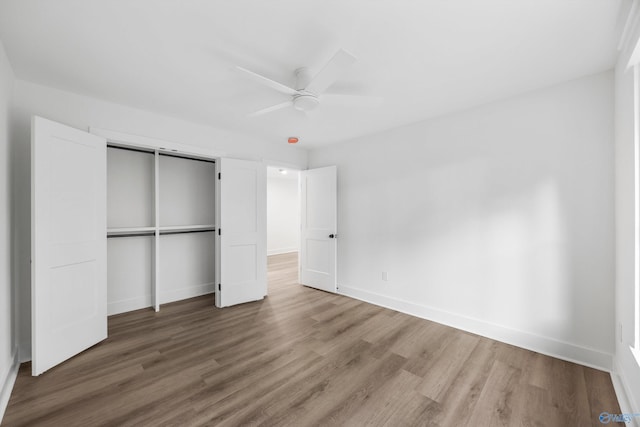 unfurnished bedroom with baseboards, ceiling fan, wood finished floors, and a closet