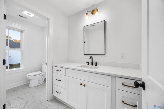 bathroom with visible vents, vanity, toilet, baseboards, and tile patterned floors