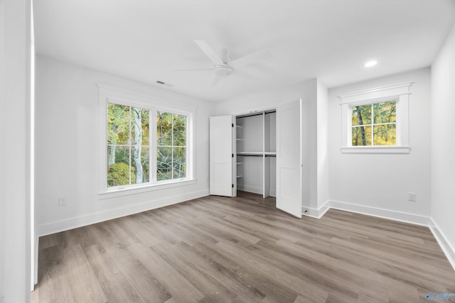 unfurnished bedroom with light hardwood / wood-style flooring, multiple windows, a closet, and ceiling fan