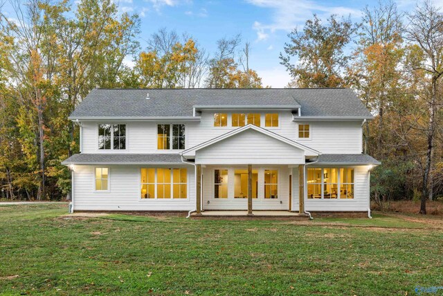back of house with a lawn and roof with shingles