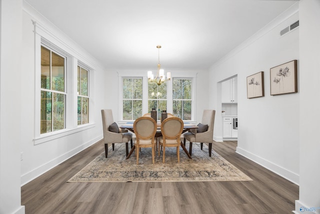 dining room featuring a notable chandelier, baseboards, dark wood-type flooring, visible vents, and ornamental molding