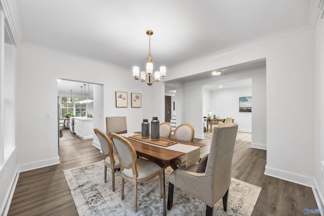 dining area with baseboards, ornamental molding, a notable chandelier, and dark wood-style floors