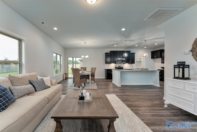 living room featuring dark hardwood / wood-style flooring, a chandelier, and sink