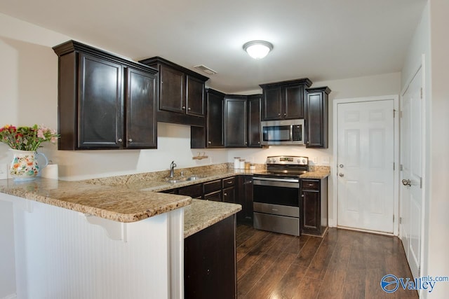 kitchen with sink, a breakfast bar area, kitchen peninsula, stainless steel appliances, and dark wood-type flooring