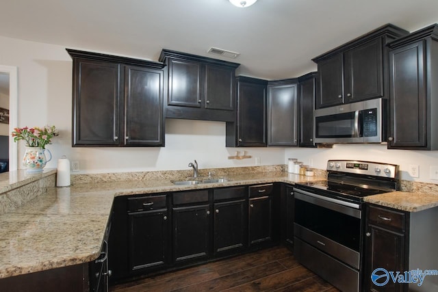 kitchen with stainless steel appliances, light stone countertops, and sink