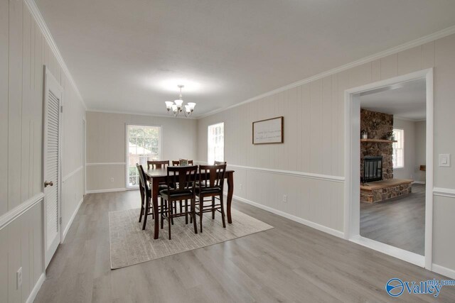 dining area with ornamental molding, light hardwood / wood-style floors, a notable chandelier, and a fireplace