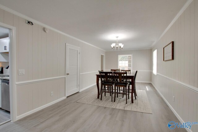 dining area featuring ornamental molding, light hardwood / wood-style flooring, and an inviting chandelier