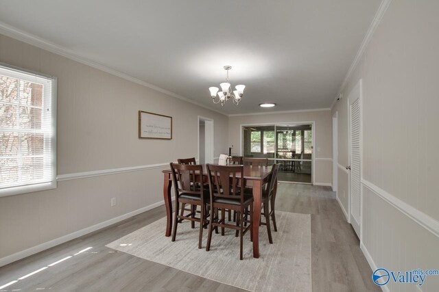 dining room featuring light wood-type flooring, an inviting chandelier, and crown molding