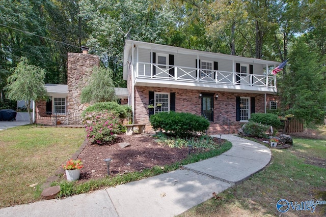 view of front of home with a balcony and a front lawn