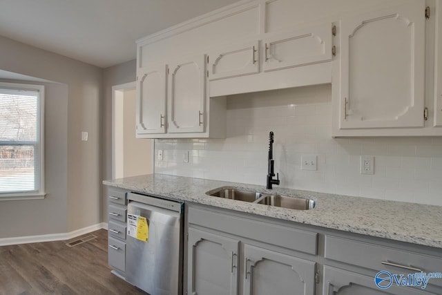 kitchen featuring sink, backsplash, dark hardwood / wood-style flooring, stainless steel dishwasher, and light stone countertops