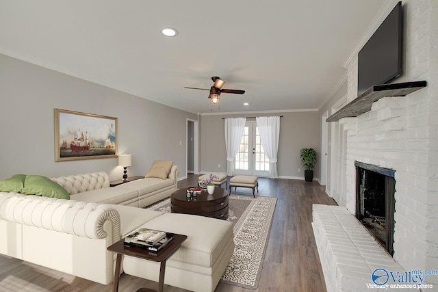 living room with crown molding, ceiling fan, hardwood / wood-style floors, a brick fireplace, and french doors